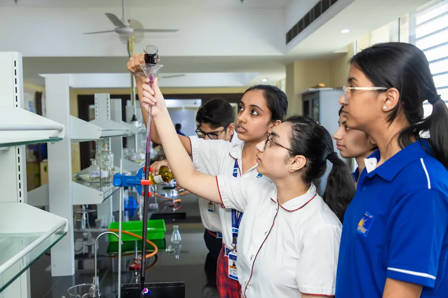 A senior girl holding a burette up to the light while her classmates watch