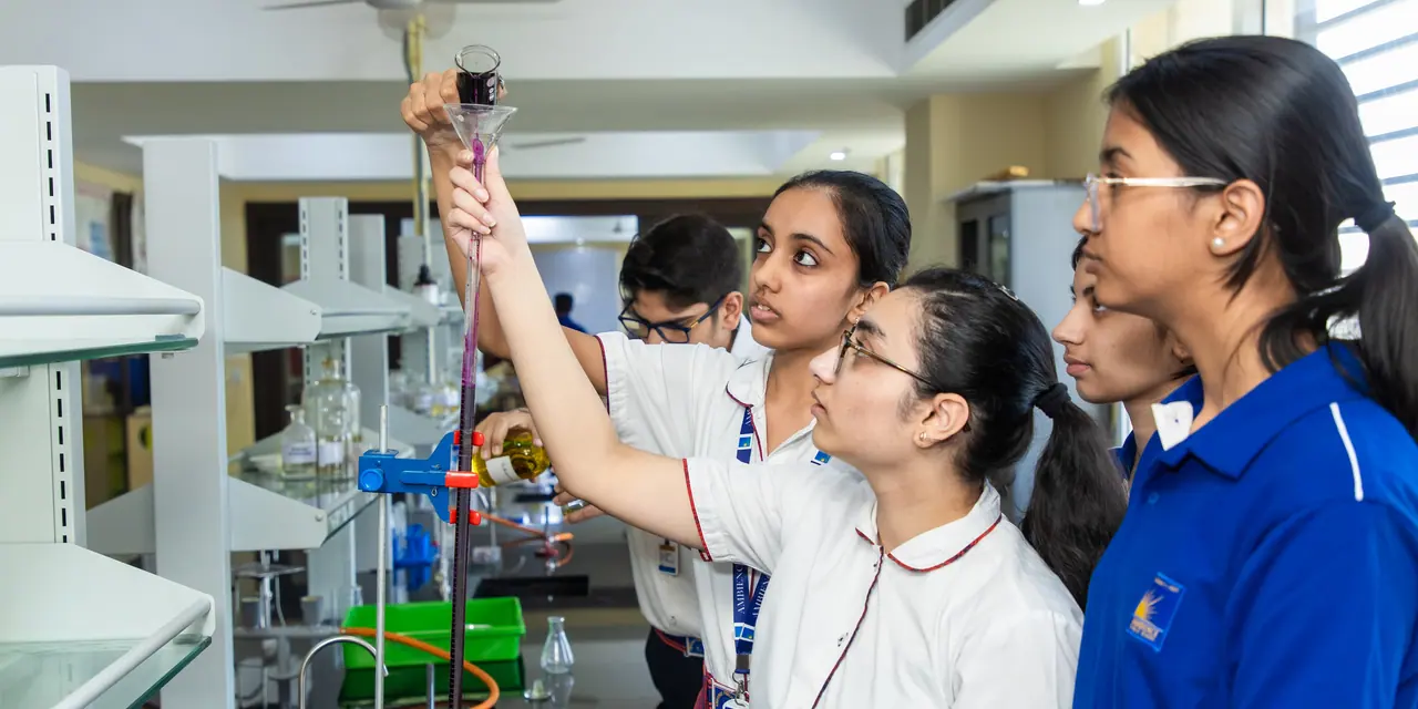 A senior girl holding a burette up to the light while her classmates watch