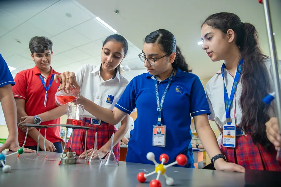 Senior girls at work in the chemistry laboratory, one pouring an orange solution