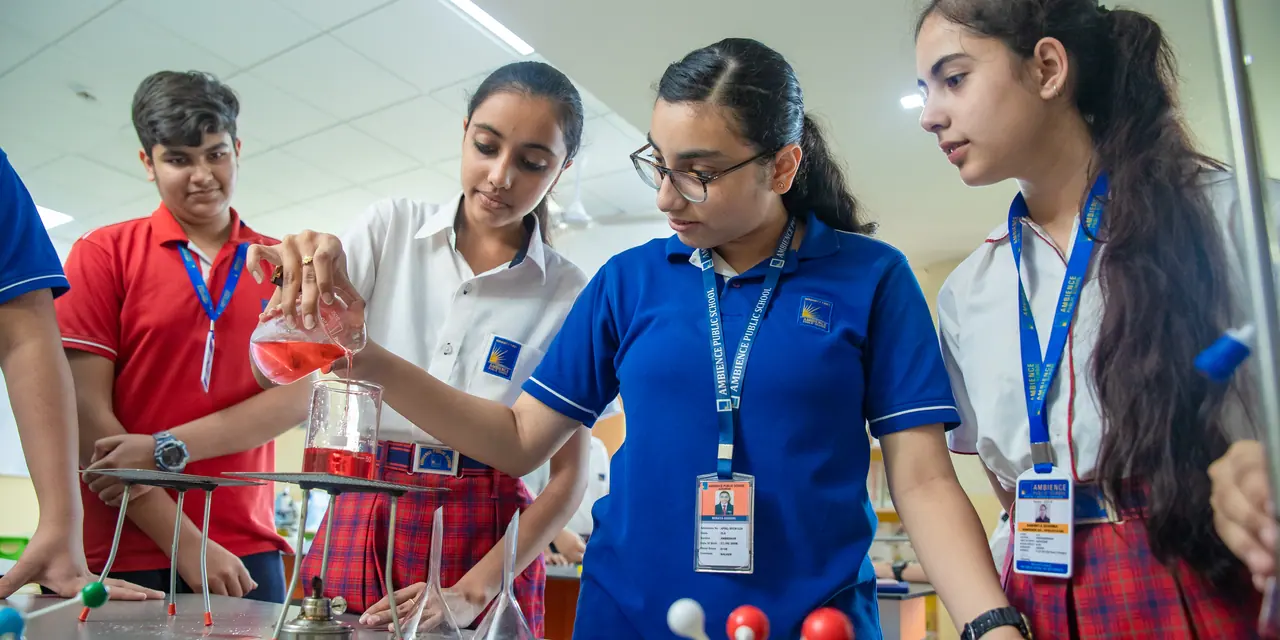 Senior girls at work in the chemistry laboratory, one pouring an orange solution