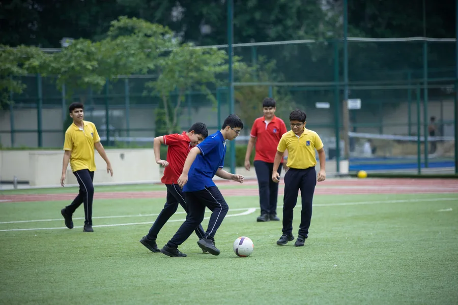 Senior boys in house colours contesting the ball on the turf