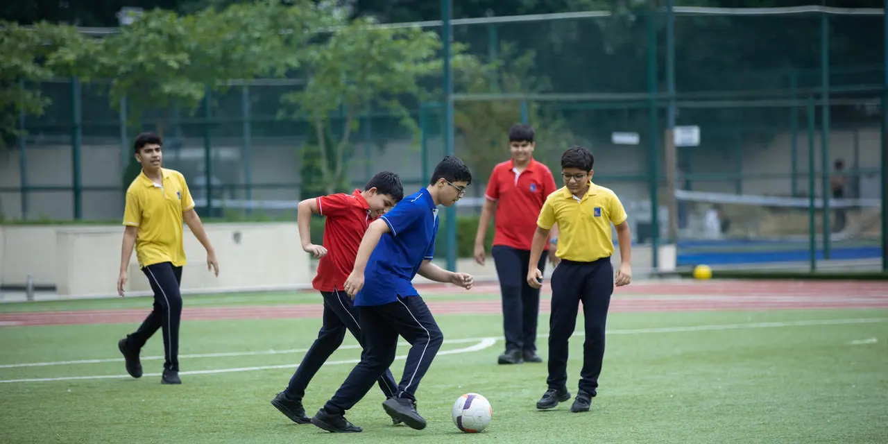 Senior boys in house colours contesting the ball on the turf