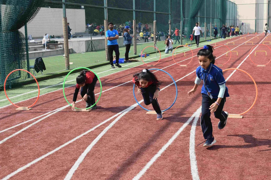 Girls stepping through red, green and blue hoops laid along the red running track