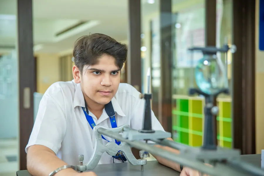 A boy concentrating on a physics apparatus in side light