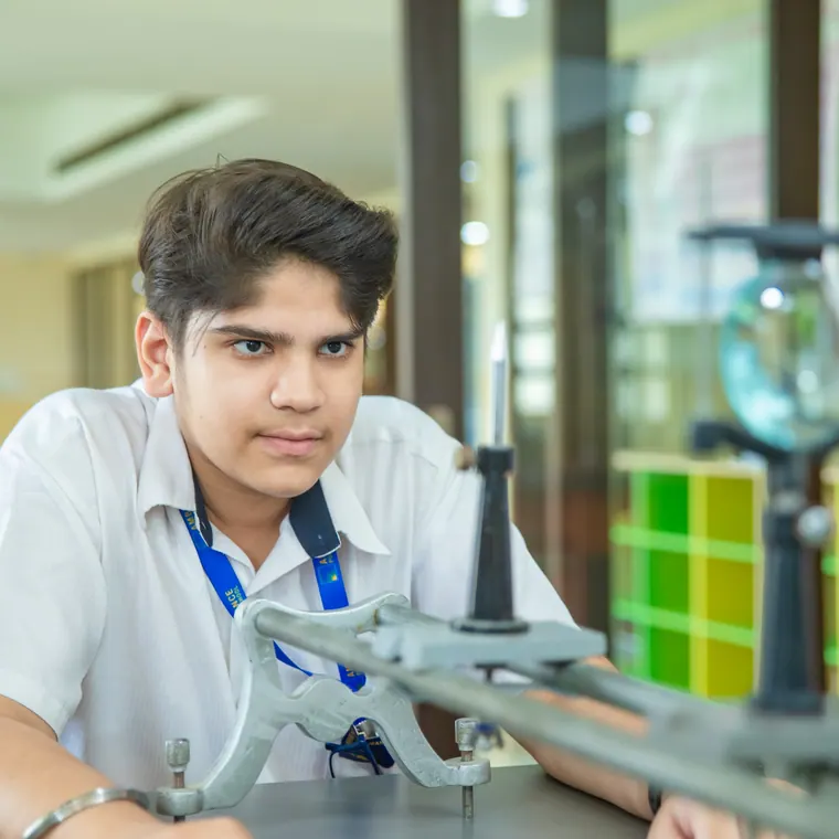 A boy concentrating on a physics apparatus in side light