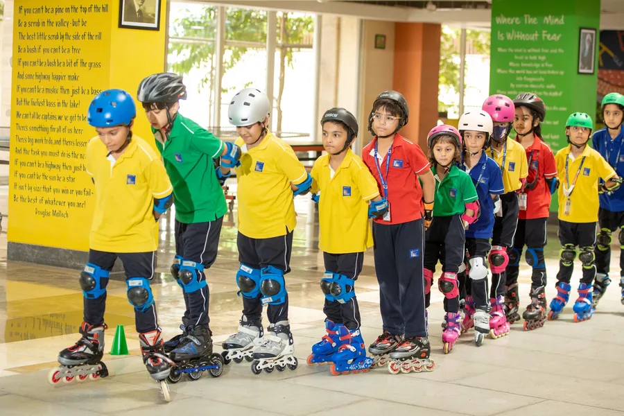 A long line of children in helmets and full pads on inline skates, waiting in the atrium