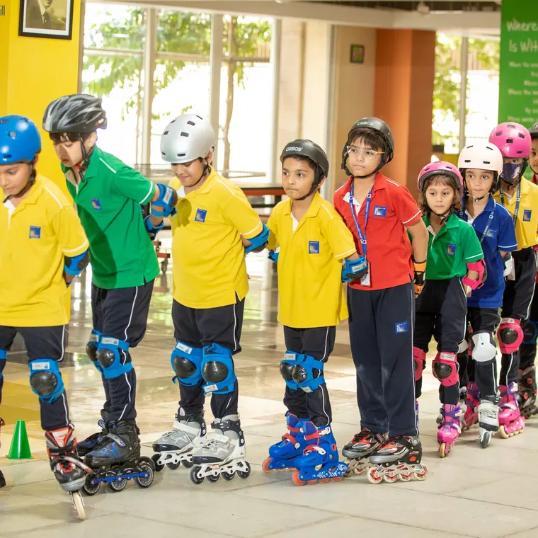 A long line of children in helmets and full pads on inline skates, waiting in the atrium